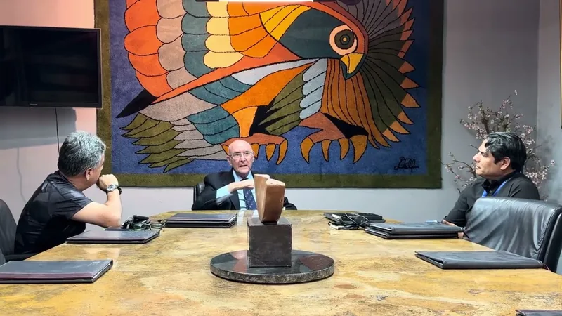El Dr. Pinkas Flint presidiendo la mesa de reuniones con dos personas.