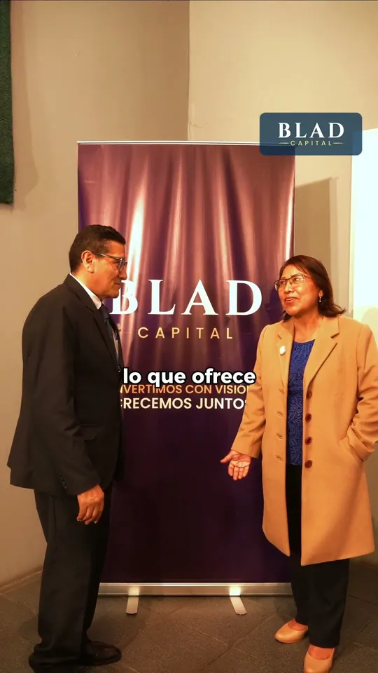 Testimonio 2: dos personas conversan de pie frente a un banner de BLAD CAPITAL.